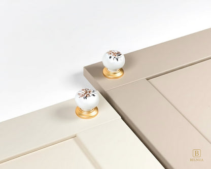 Belnua - ZERRA porcelain/ceramic white knob with golden arch bloom motif showcasing with cream and cashmere cabinet door