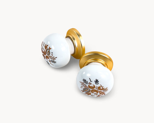 Belnua - Top detail flat lay view of ZERRA white cabinet porcelain/ceramic knob with matte gold finish and golden arch motif