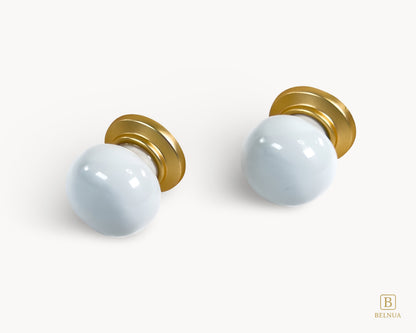 Front angled flat lay view of two Zerra white porcelain knobs with gold base | Belnua