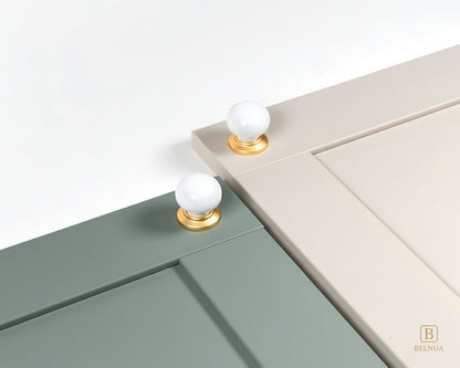 Close-up of a sage green and cashmere cabinet doors with Zerra white ceramic knobs and gold bases | Belnua
