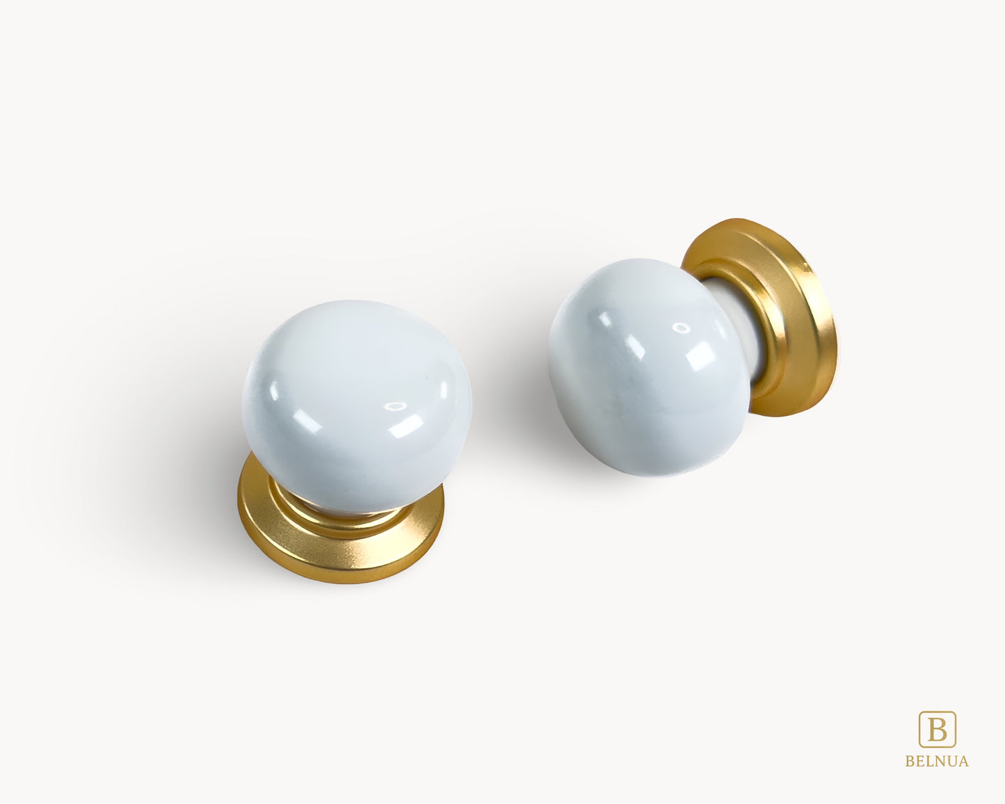 Angled flat lay and top view of two Zerra white porcelain / ceramic knobs with gold base | Belnua