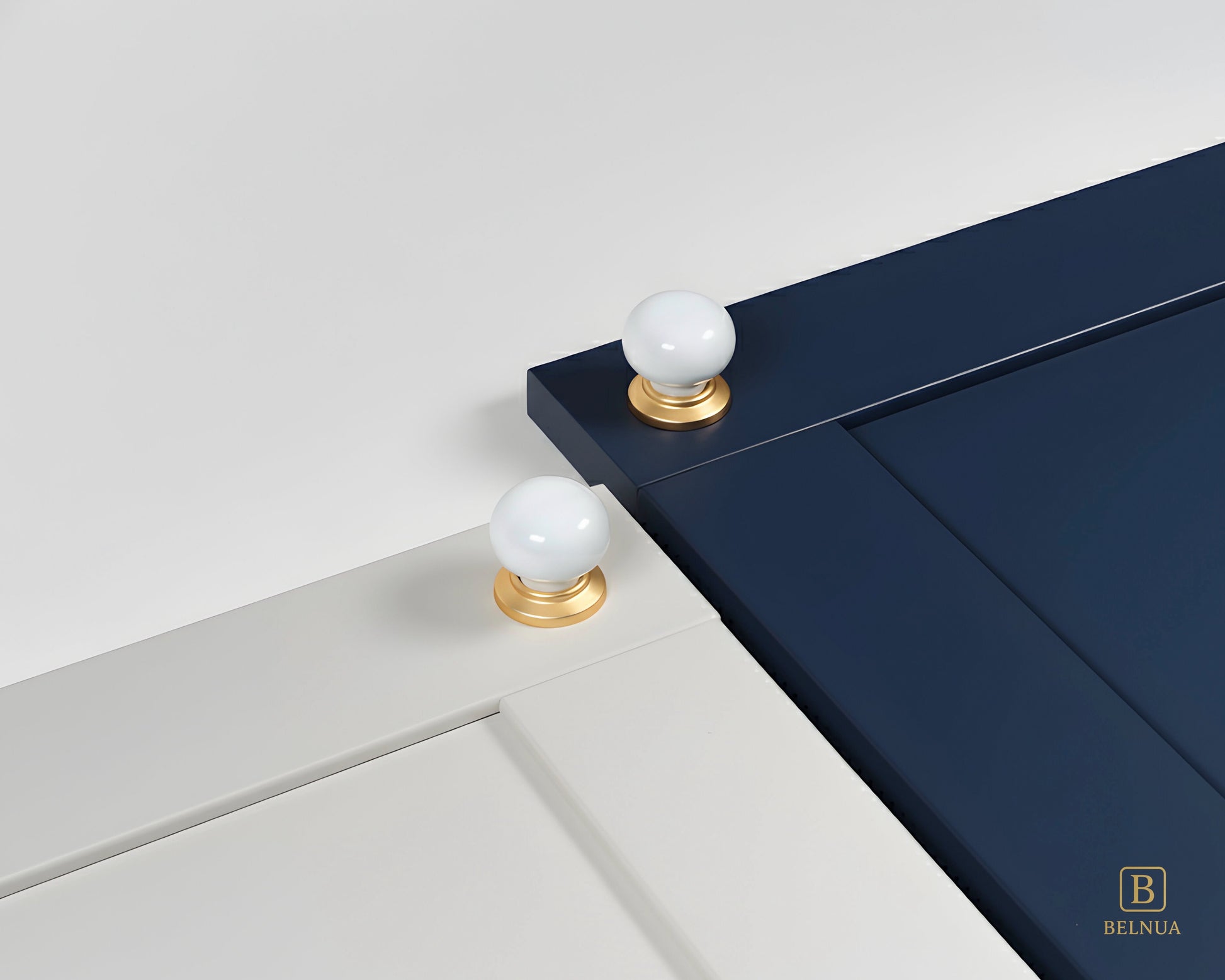 Close-up of a navy blue and porcelain white cabinet doors with Zerra white ceramic knobs and gold bases | Belnua