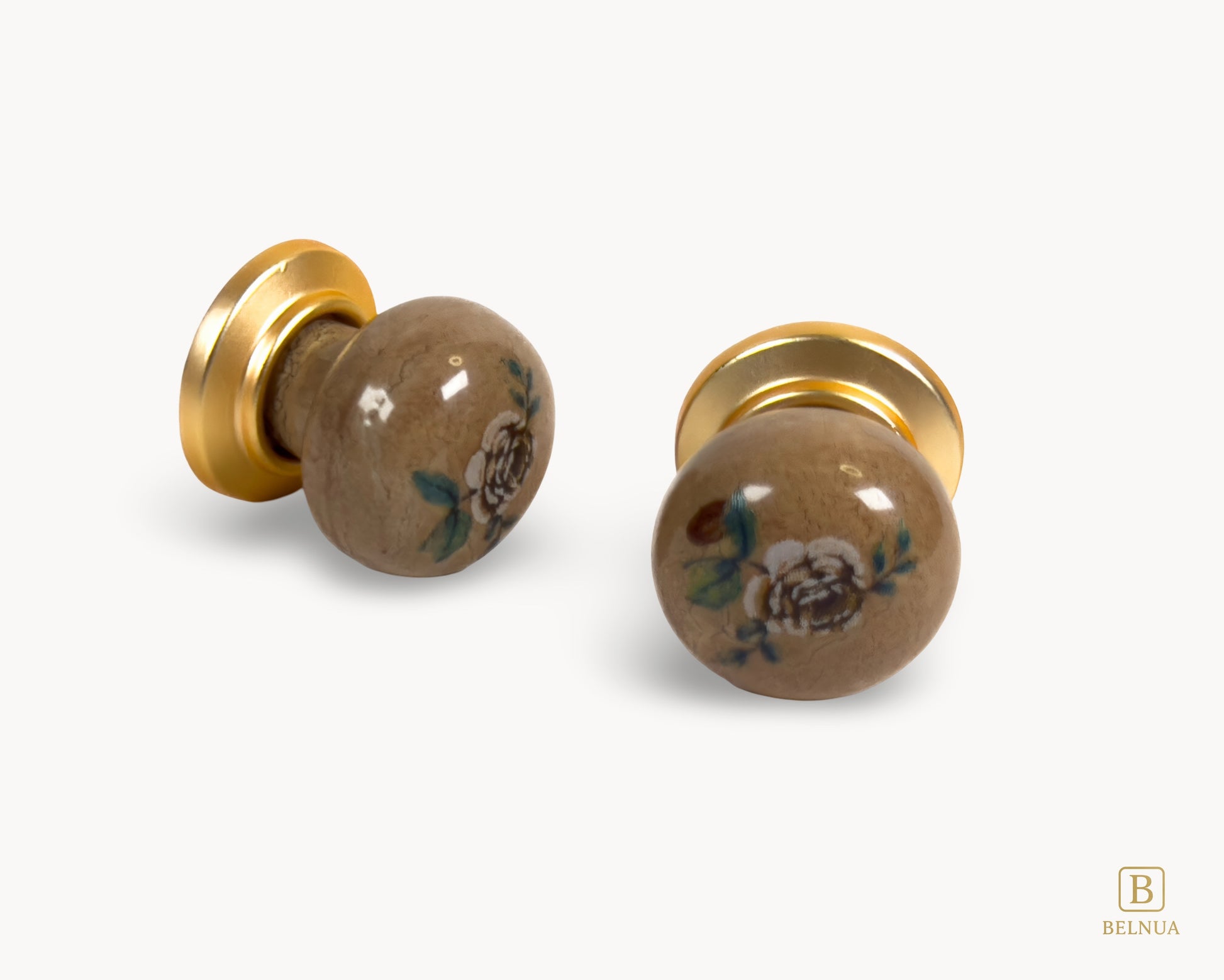 Belnua - Flat lay angled view of ZERRA ceramic knob pair showing matte gold finish and rose motif