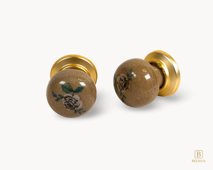 Belnua - Flay lay angled view of ZERRA ceramic/porcelain knobs showing pair matte gold finish and rose motif