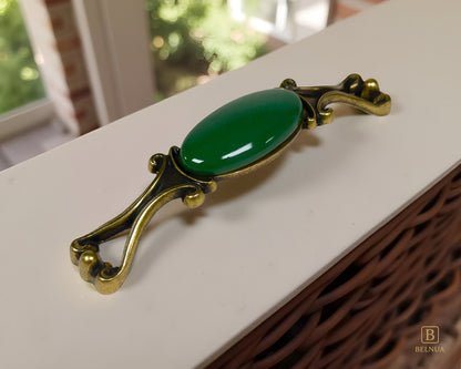 Belnua - A Nureya decorative cabinet handles with dark green porcelain and brass base  on a light grey surface