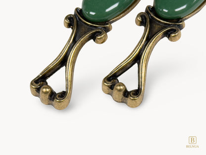 Belnua - Front view of Nureya decorative cabinet handle pair with dark green porcelain and brass base  on a white surface