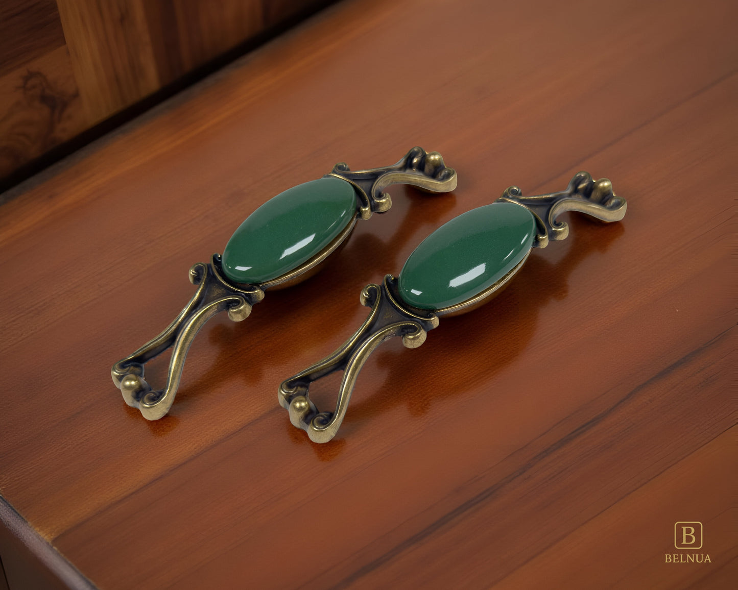 Belnua - Pair of Nureya decorative cabinet handles with dark green porcelain and brass base  on a dark oak table