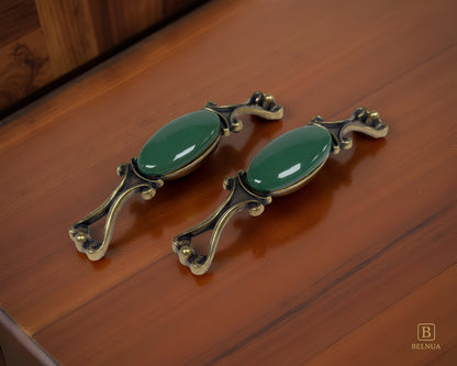 Belnua - Pair of Nureya decorative cabinet handles with dark green porcelain and brass base  on a dark oak table