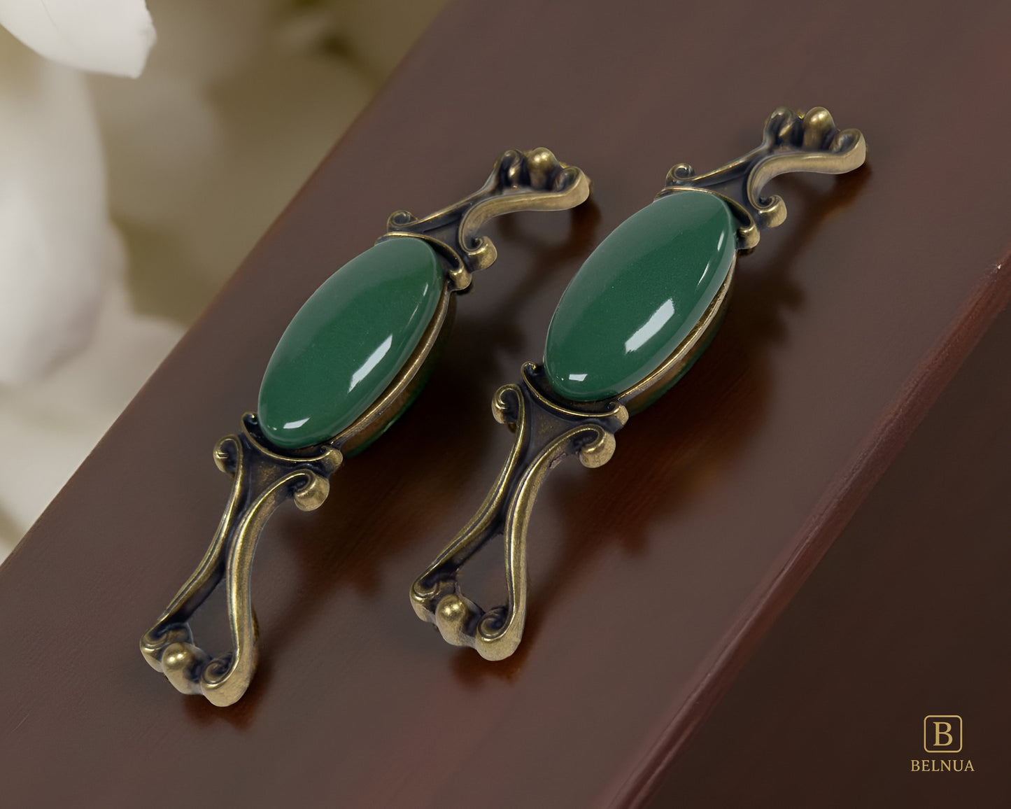 Belnua - Pair of Nureya decorative cabinet handles with dark green porcelain and brass base  on a walnut wood surface