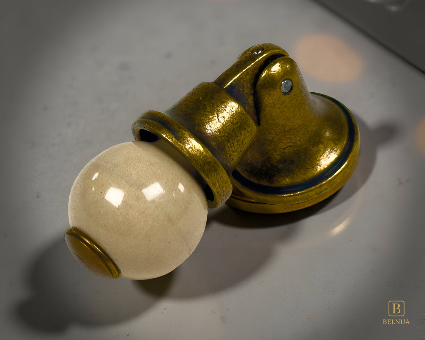 Belnua - Close-up of orange porcelain insert and sculptural antique brass base on marble worktop from Virella collection