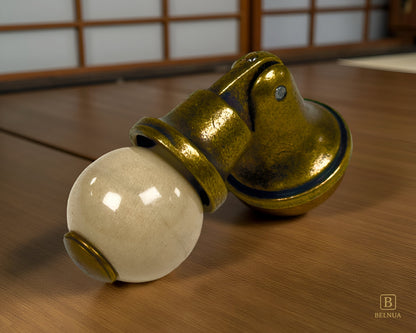 Belnua - Close-up of orange porcelain insert and sculptural antique brass base on oak surface
