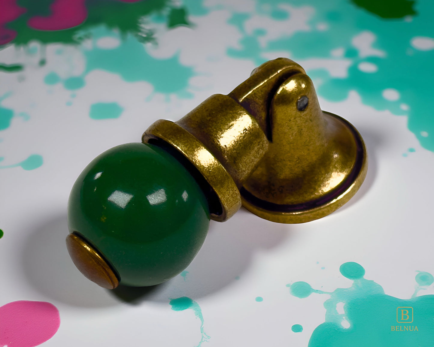 Belnua - Close-up of sculptural angled brass base and green porcelain knob with splashed colour background