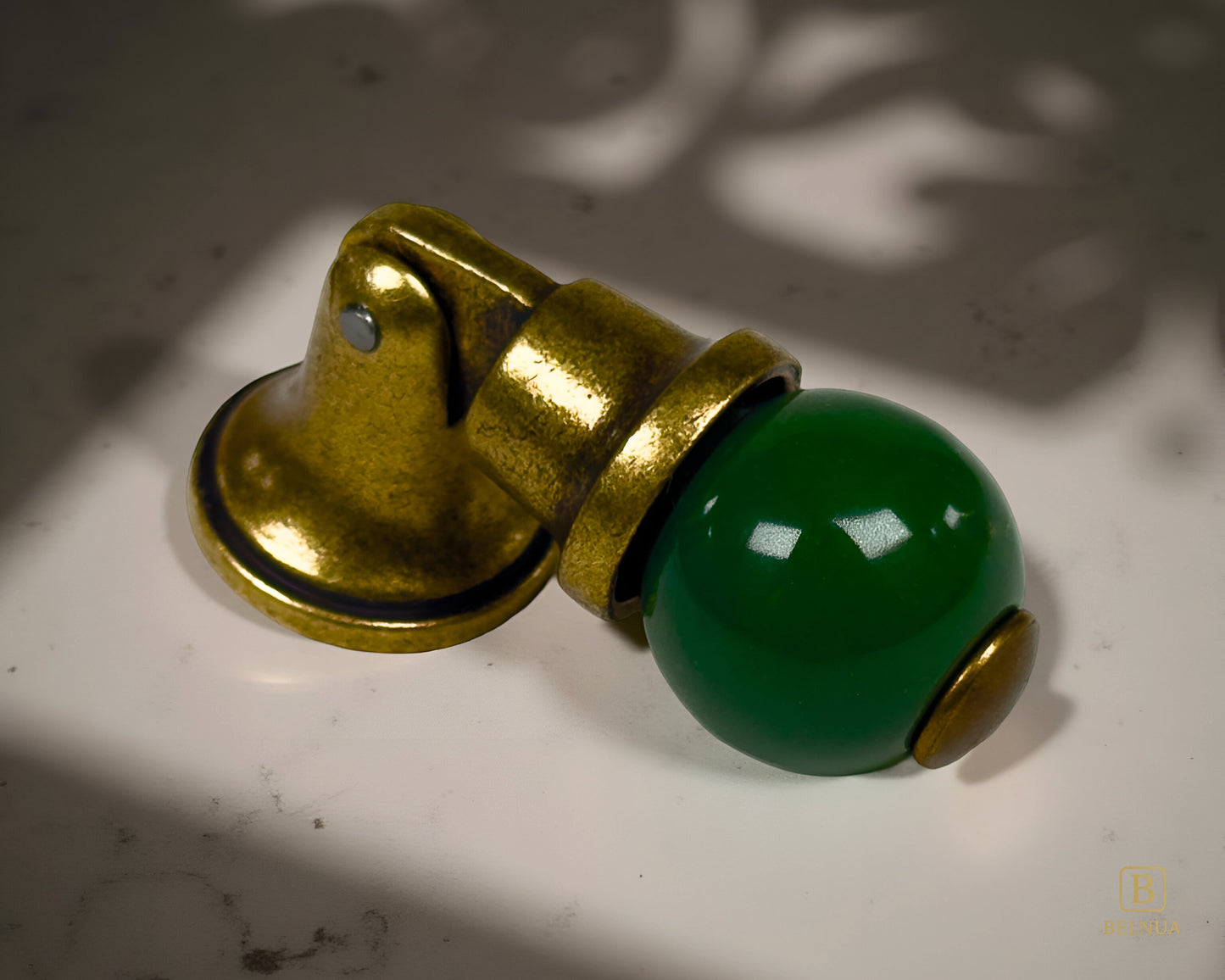 Belnua - Right angled view of green VIRELLA porcelain/ceramic cabinet knob with sculptural form of brass base with shadow and beige background