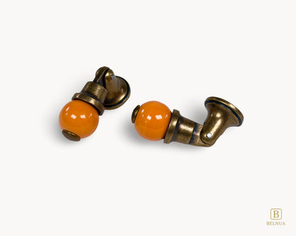 Belnua - Flat lay of Virella antique brass knob pairs with orange porcelain insert