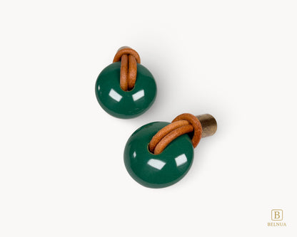 Overhead view of green porcelain and antique brass knobs, highlighting the circular design and leather loop detail.