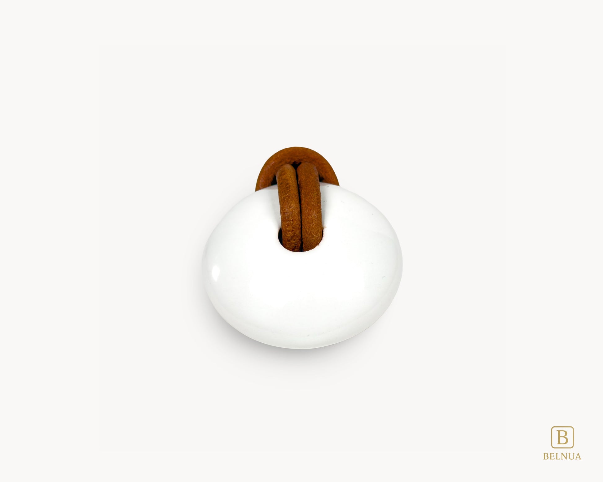 Direct top-down view of the circular white porcelain surface with an antique brass core and leather loop.