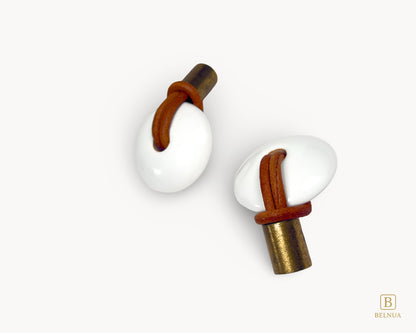 Side profile view illustrating how the antique brass base and leather loop project from the white porcelain face.